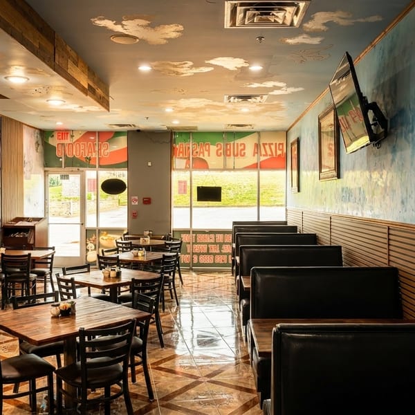 Empty restaurant interior with wooden tables, black chairs, booth seating, and a cloud-painted ceiling.